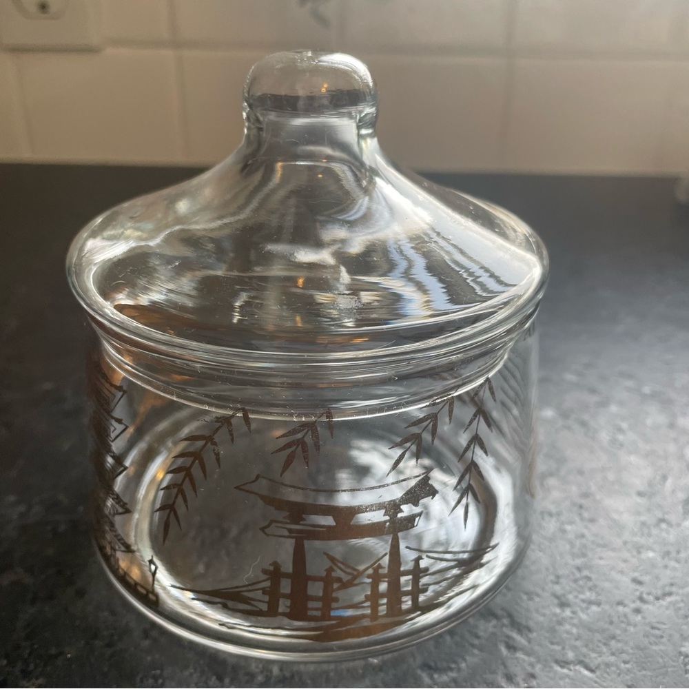 Round clear glass trinket jar with a lid, adorned with gold Asian symbols